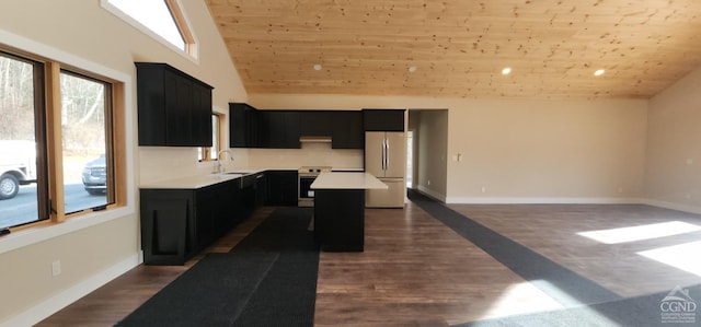 kitchen featuring sink, vaulted ceiling, appliances with stainless steel finishes, a kitchen island, and dark hardwood / wood-style flooring