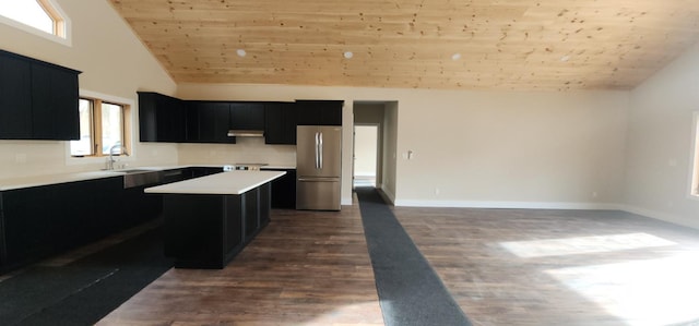 kitchen with dark hardwood / wood-style floors, a center island, sink, and stainless steel refrigerator