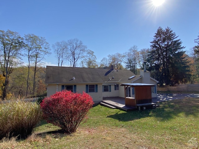 rear view of house with a lawn and a wooden deck