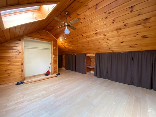 additional living space featuring wood ceiling, wood walls, vaulted ceiling with skylight, and wood-type flooring