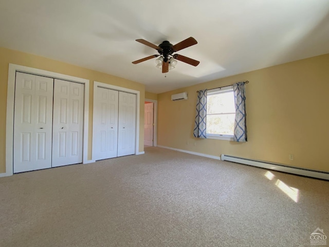 unfurnished bedroom with a wall mounted air conditioner, two closets, ceiling fan, a baseboard radiator, and carpet floors