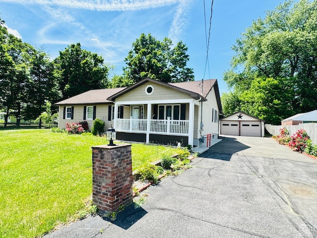 view of front of home featuring an outbuilding, a detached garage, fence, covered porch, and a front yard