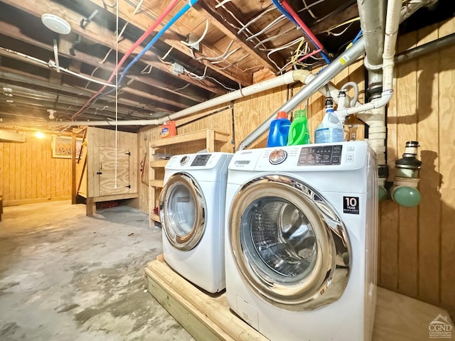 laundry room featuring laundry area, wood walls, and separate washer and dryer