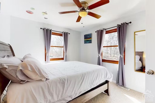 bedroom featuring light carpet, visible vents, multiple windows, and a ceiling fan