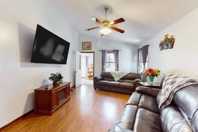 living area featuring lofted ceiling, light wood-style flooring, a ceiling fan, and baseboards