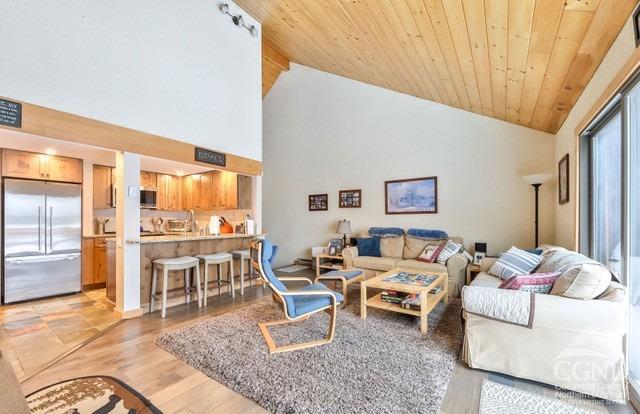 living room with light hardwood / wood-style floors, wood ceiling, and high vaulted ceiling