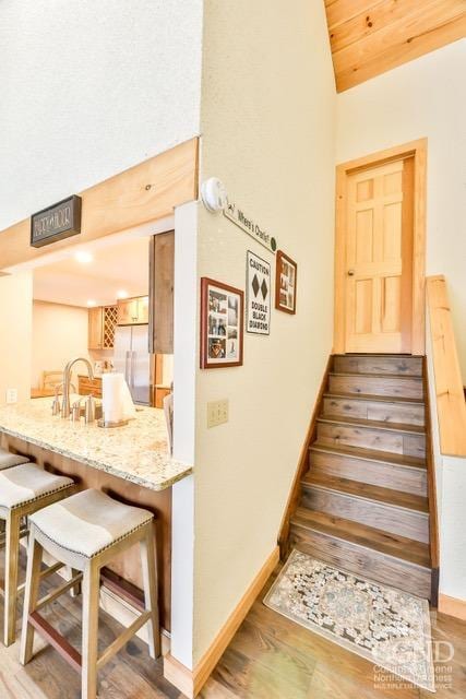 staircase with vaulted ceiling, wood-type flooring, sink, and wooden ceiling