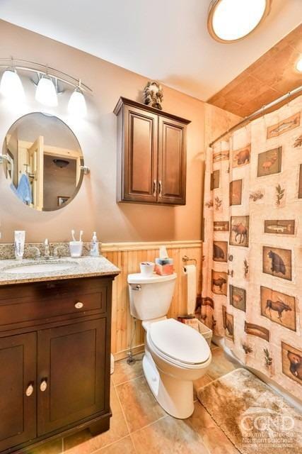 bathroom featuring vanity, tile patterned floors, wooden walls, a shower with shower curtain, and toilet