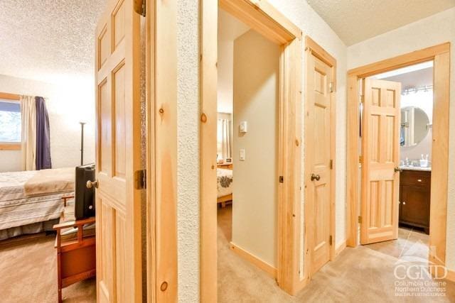 hallway featuring a textured ceiling and light colored carpet