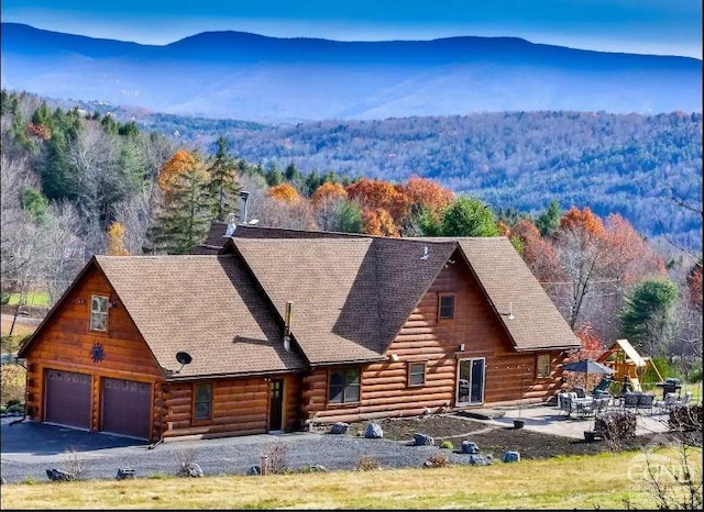 log cabin with a garage, a mountain view, and a patio