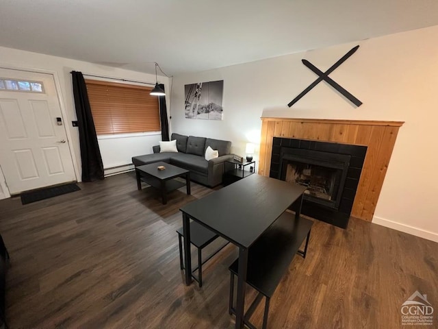 living room with a tile fireplace, dark hardwood / wood-style flooring, and a baseboard heating unit