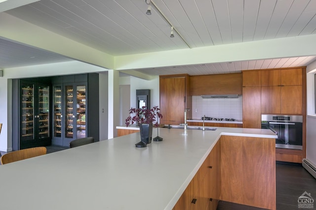 kitchen featuring dark wood-style floors, modern cabinets, stainless steel appliances, light countertops, and backsplash