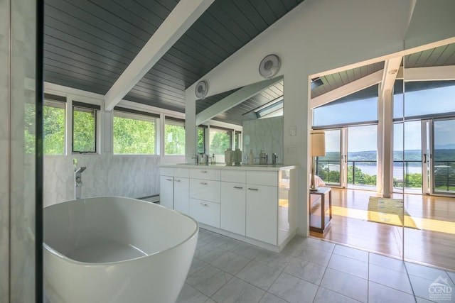 bathroom featuring a wealth of natural light, a water view, vaulted ceiling with beams, and double vanity