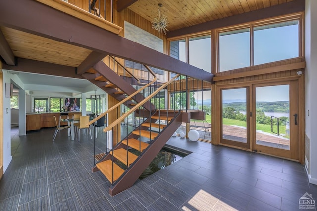 staircase featuring a chandelier, wooden ceiling, a high ceiling, and beam ceiling