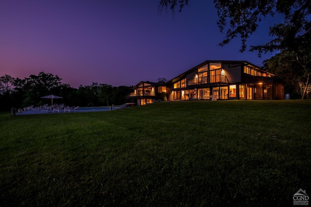 rear view of house with a lawn and an outdoor pool