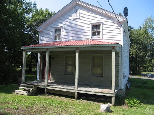 rear view of house featuring a yard and covered porch