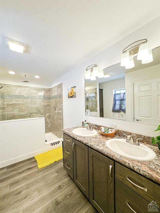 bathroom featuring hardwood / wood-style flooring, vanity, and a tile shower