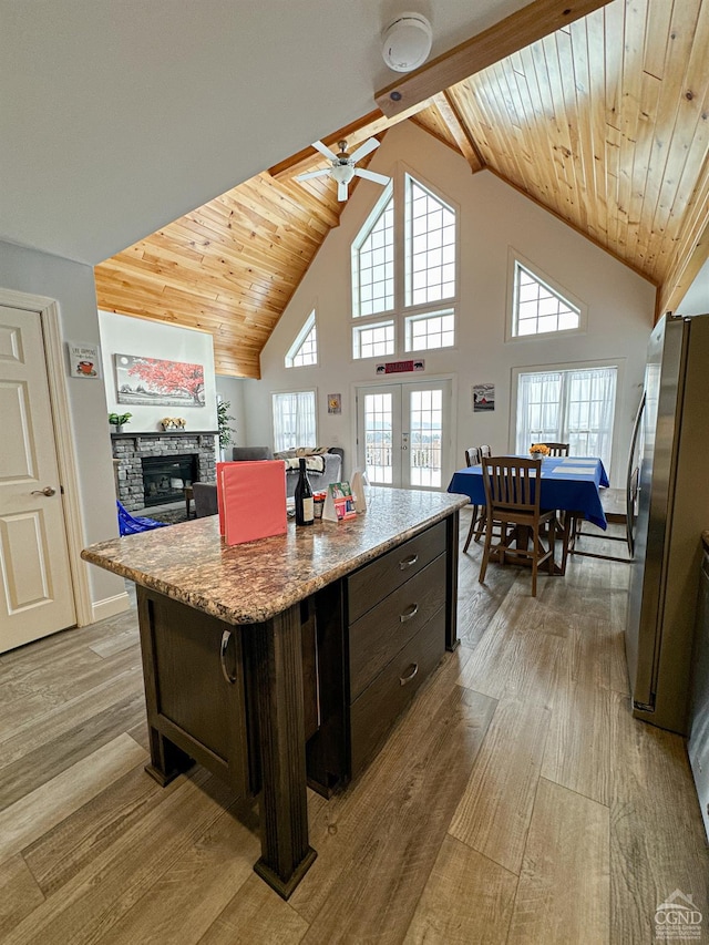 kitchen with dark brown cabinetry, french doors, stainless steel fridge, a kitchen island, and light wood-type flooring