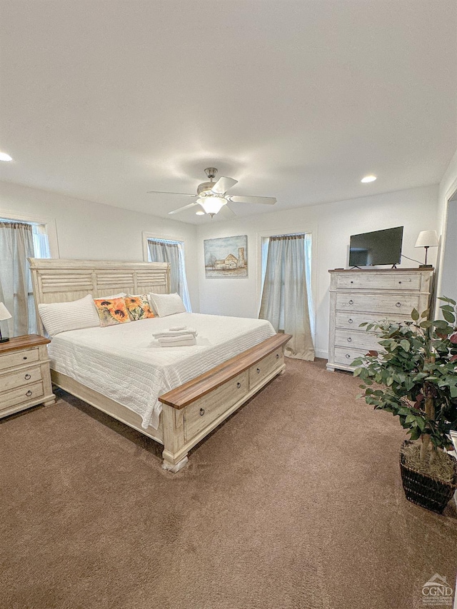 carpeted bedroom featuring multiple windows and ceiling fan