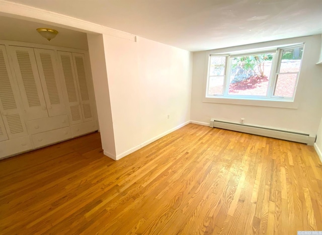 spare room with a baseboard radiator and light wood-type flooring