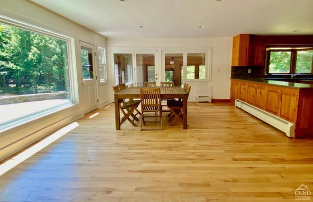 dining space with baseboard heating, plenty of natural light, and light wood-type flooring