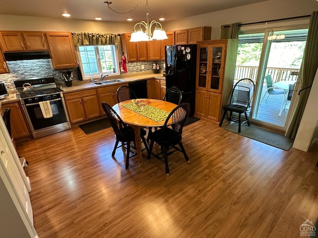 kitchen featuring backsplash, pendant lighting, black appliances, and light wood-type flooring