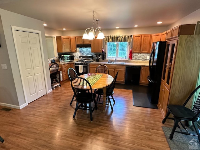 kitchen featuring hardwood / wood-style floors, pendant lighting, a chandelier, and black appliances