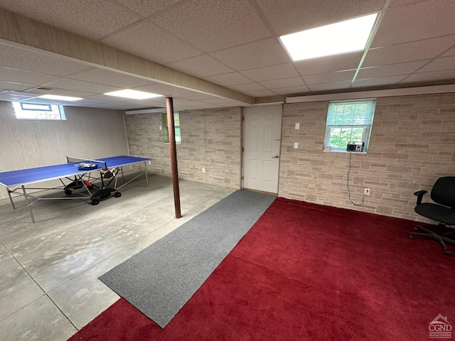 rec room with a paneled ceiling and concrete floors