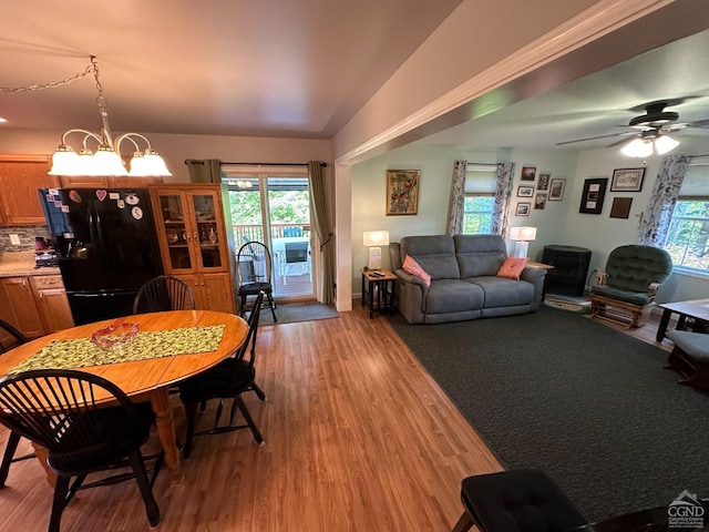 dining room featuring a wealth of natural light, ceiling fan with notable chandelier, light hardwood / wood-style floors, and vaulted ceiling