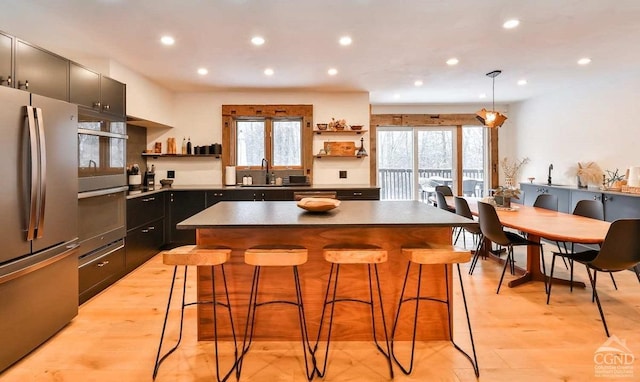 kitchen featuring a kitchen bar, stainless steel appliances, a kitchen island, and light hardwood / wood-style floors