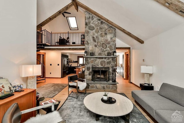 living room featuring beam ceiling, a stone fireplace, light hardwood / wood-style floors, and high vaulted ceiling