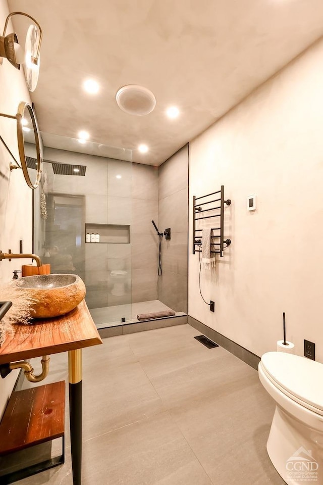 bathroom featuring toilet, a tile shower, and sink