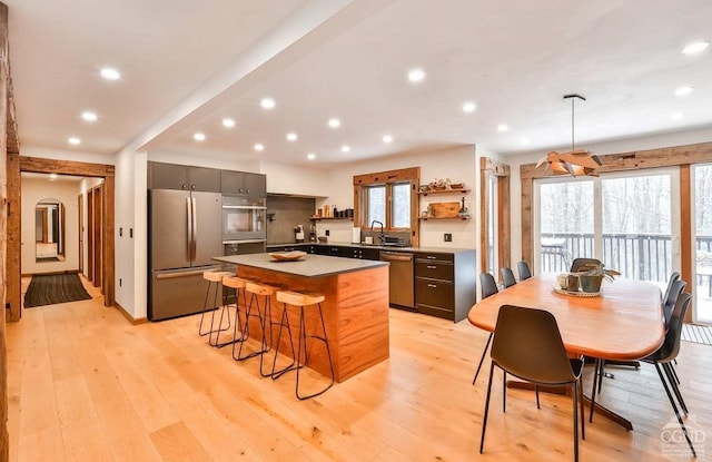 kitchen featuring a kitchen island, light hardwood / wood-style floors, stainless steel appliances, and a breakfast bar area