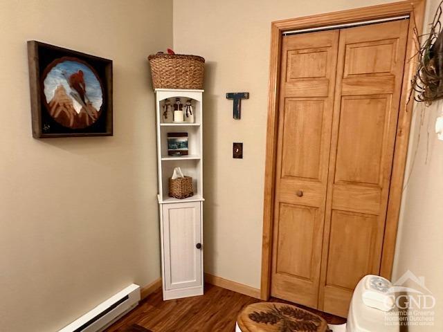 hall with baseboard heating and dark wood-type flooring