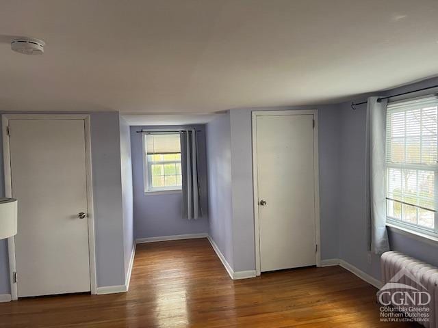 unfurnished bedroom with radiator, baseboards, and wood finished floors