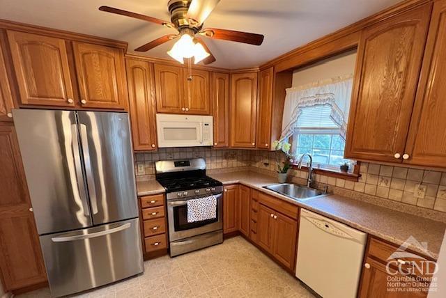 kitchen with a sink, a ceiling fan, brown cabinetry, and stainless steel appliances