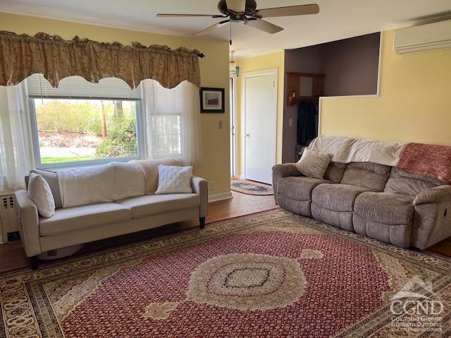 living area with baseboards, ceiling fan, wood finished floors, and a wall mounted air conditioner