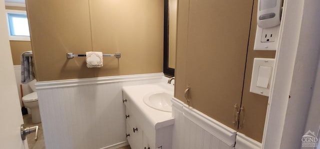 bathroom with a decorative wall, a wainscoted wall, and vanity