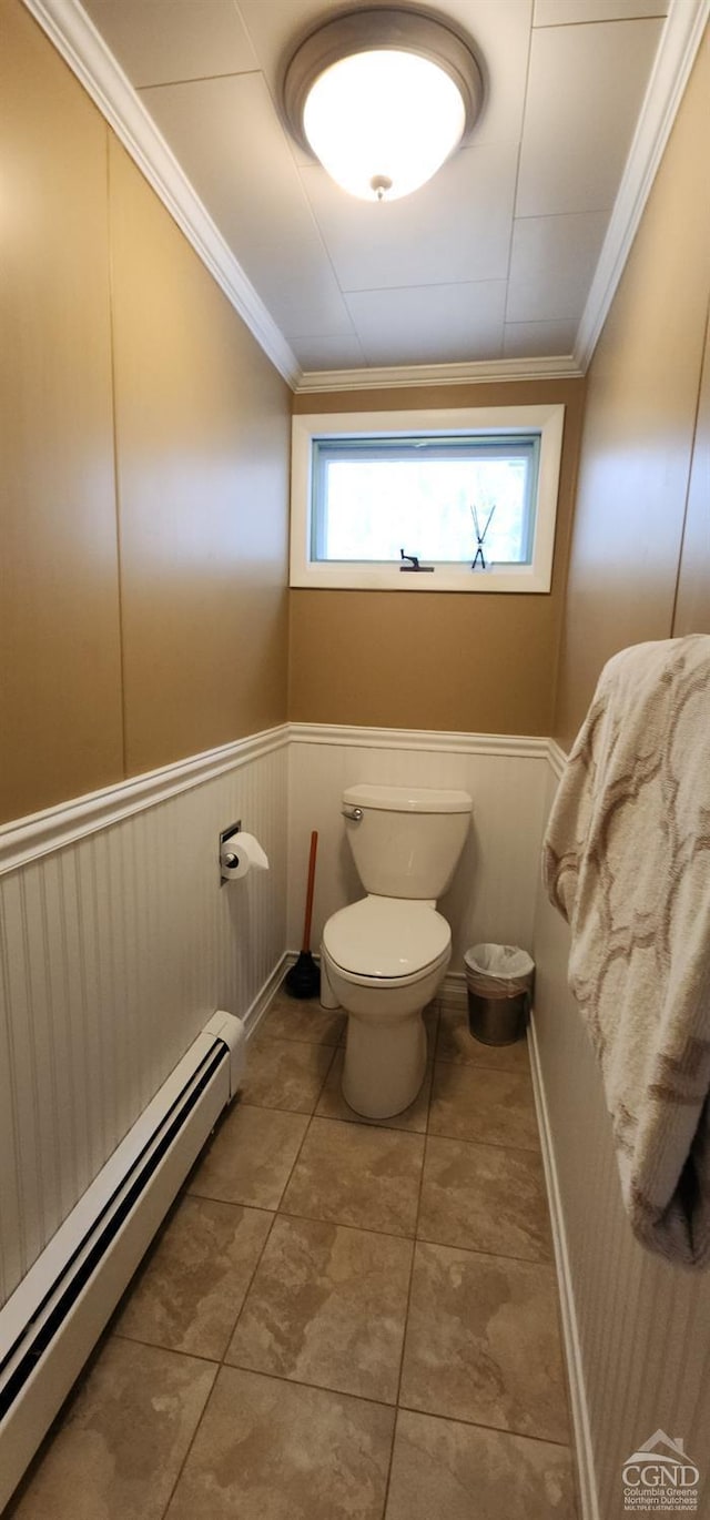 bathroom with crown molding, toilet, a baseboard heating unit, and wainscoting
