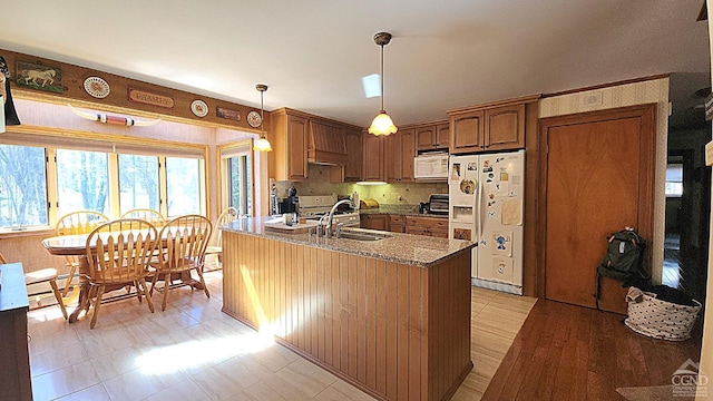 kitchen featuring dark stone countertops, sink, hanging light fixtures, and white appliances