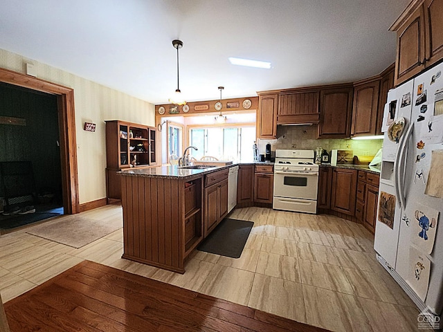 kitchen featuring kitchen peninsula, white appliances, sink, pendant lighting, and range hood