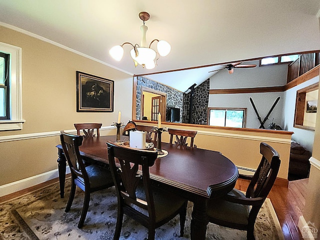 dining space featuring hardwood / wood-style flooring, ceiling fan with notable chandelier, crown molding, and vaulted ceiling