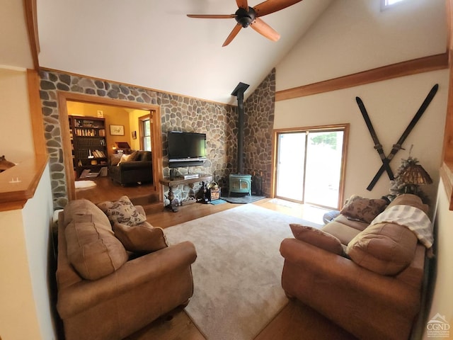 living room with hardwood / wood-style flooring, ceiling fan, a wood stove, and high vaulted ceiling