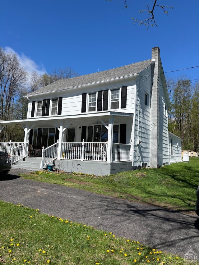 view of front of property featuring a porch, a chimney, and a front lawn