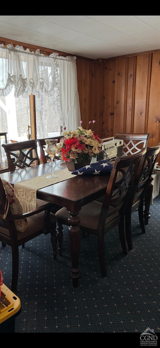 carpeted dining room with wooden walls