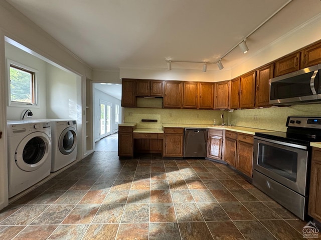 kitchen with appliances with stainless steel finishes, washing machine and dryer, a wealth of natural light, and sink