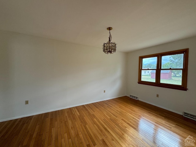 unfurnished room with a notable chandelier and light hardwood / wood-style flooring