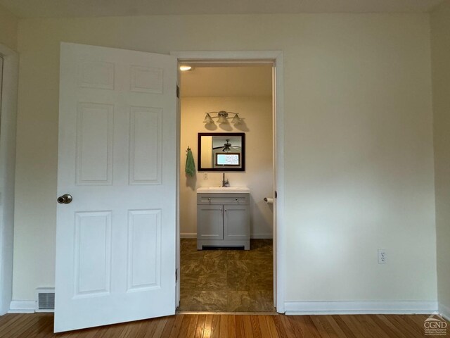 unfurnished bedroom with ensuite bath, sink, and wood-type flooring