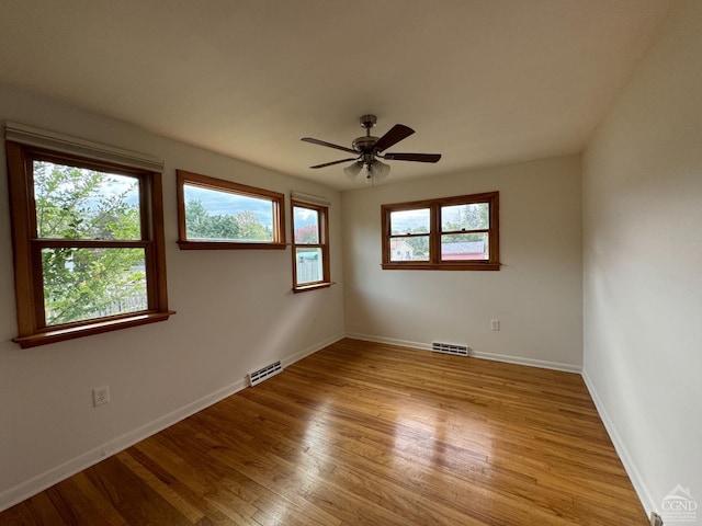 empty room featuring plenty of natural light, light hardwood / wood-style floors, and ceiling fan