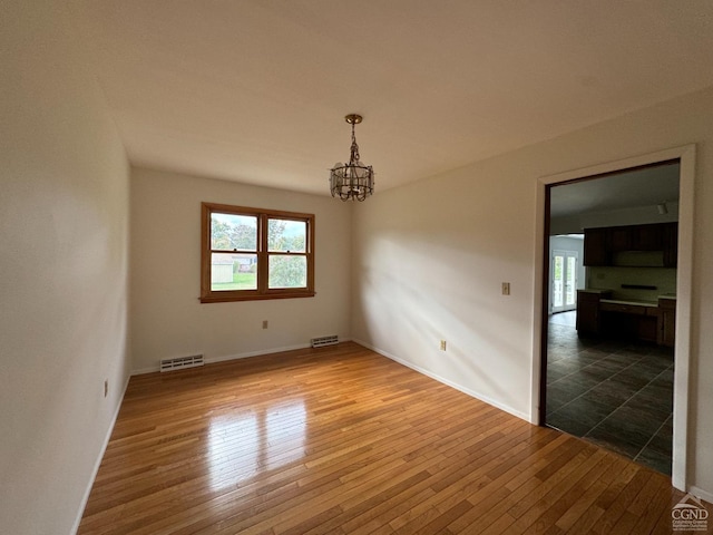 unfurnished room with hardwood / wood-style flooring and a notable chandelier